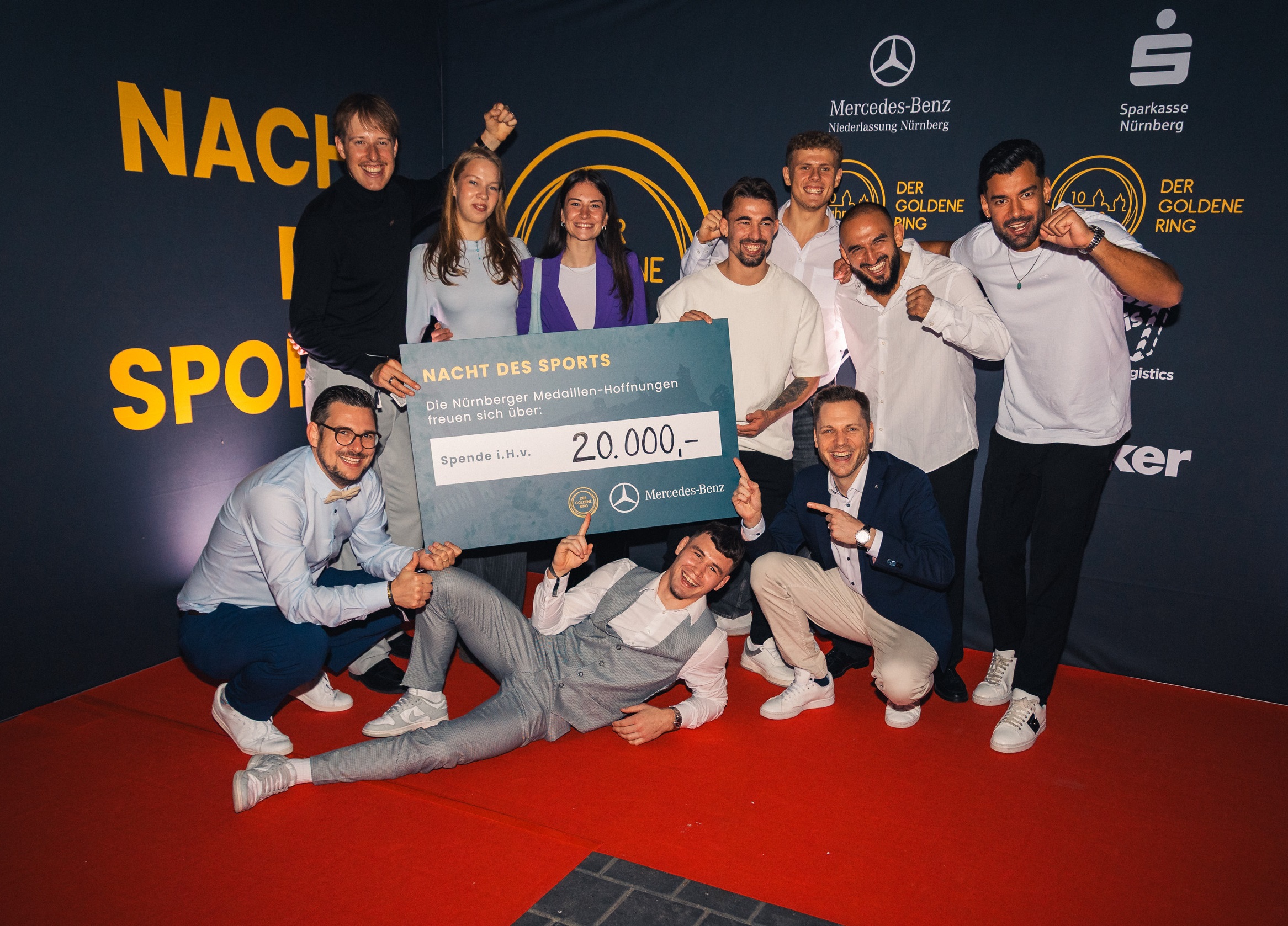 Auf dem Foto (v. l.) 20.000 Euro konnte der GOLDENE RING aus Ticketeinnahmen und Tombola-Erlösen für die Stipendien seiner Spitzensportler:innen bei der NACHT DES SPORTS sammeln. Die GOLDENER RING Vorstände Christopher Wesley (unten links) und Benny Jung (unten rechts) freuen sich mit aktiven und ehemaligen Stipendiat:innen des Vereins (v. l.) Simon Henseleit (Triathlon), Rostislav Leicht (Ringen) (liegend), Daria Tontsch (Synchronschwimmen), Ela Aydin (Taekwondo), Deniz Menekse (Ringen), Jakob Kemminer (Sprint), Roland Schwarz (Ringen) und Tahir Gülec (Taekwondo). (Foto: DC-Fotografie, Daniel Engelhardt)