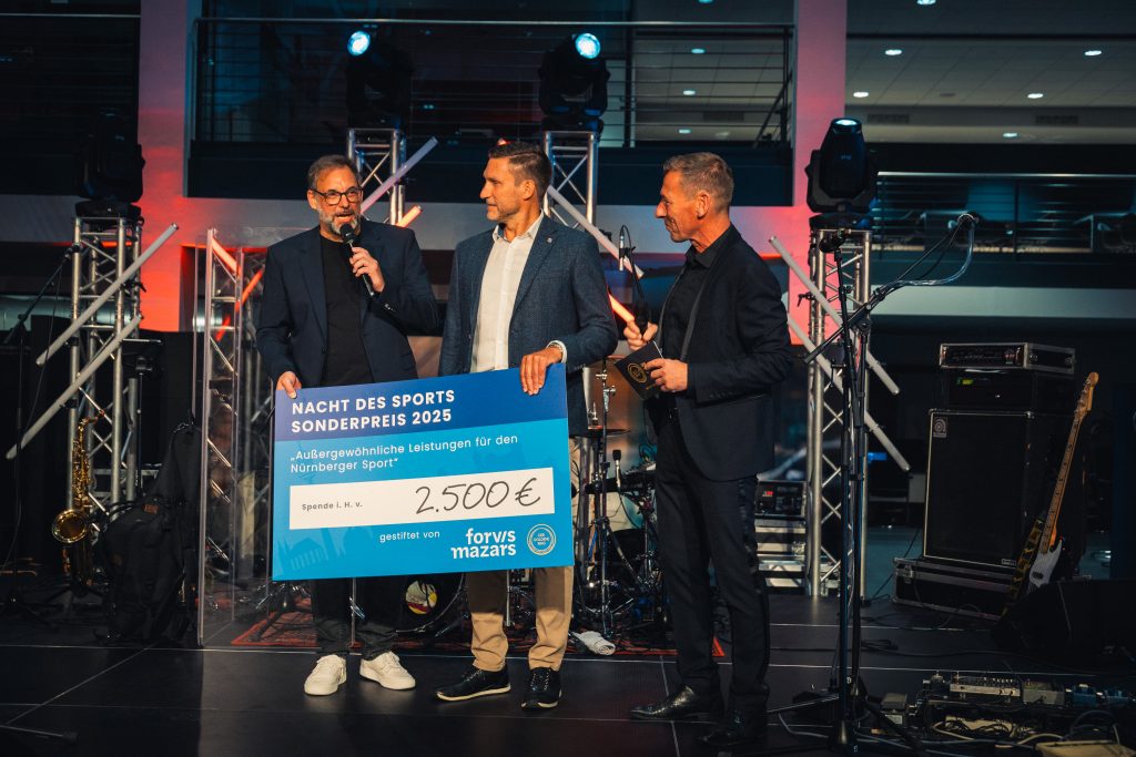 Andreas Klenk, Partner bei Forvis Mazars überreicht den mit 2.500 Euro dotierten Sonderpreis auf der Bühne der NACHT DES SPORTS 2025 an Norbert Wörlein vom TSV Ochenbruck.
